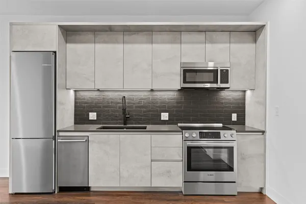 a kitchen with stainless steel appliances granite countertop a stove a sink and a microwave