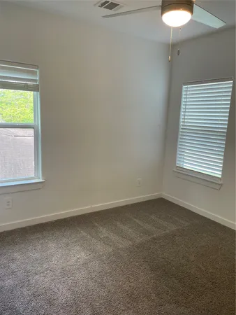 an empty room with a window and a chandelier fan