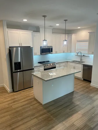 an open kitchen with granite countertop kitchen island wooden floor center island stainless steel appliances and cabinets
