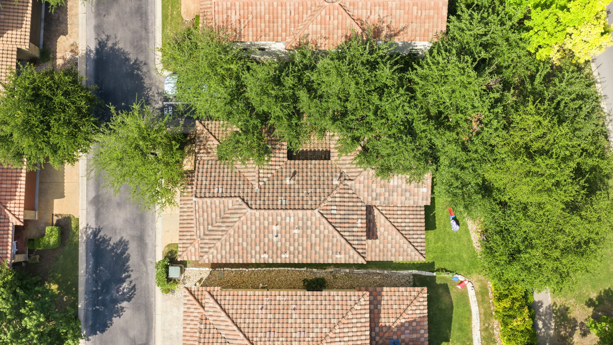 15317 Falconhead Grove Loop Austin, TX 78738 - Photo 33 of 36 Aerial view showcasing a property with a multi-gabled tile roof, mature trees, and a green lawn