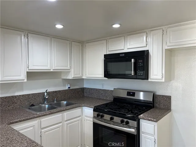 a kitchen with granite countertop white cabinets and stainless steel appliances