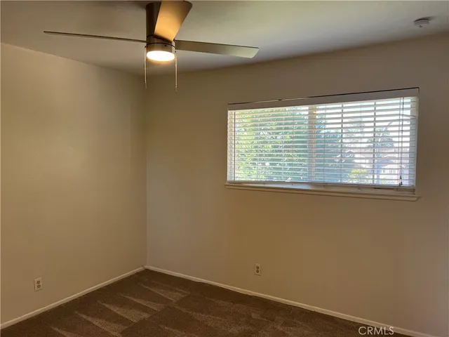 an empty room with closet and a ceiling fan
