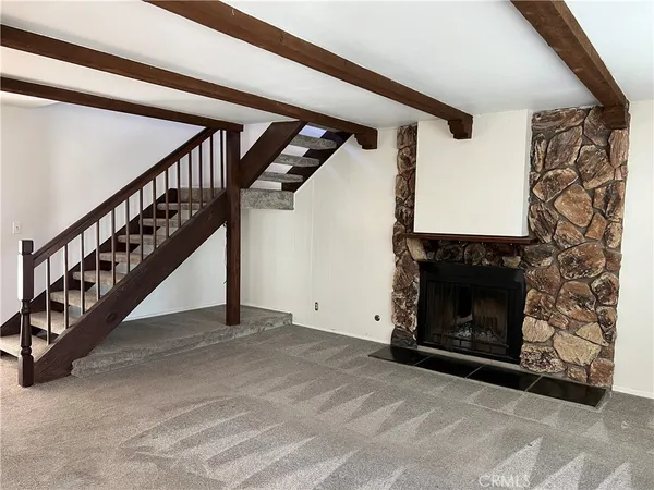 a view of an empty room with wooden floor a fireplace and a window