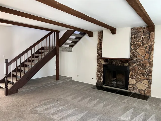 a view of an empty room with wooden floor a fireplace and a window