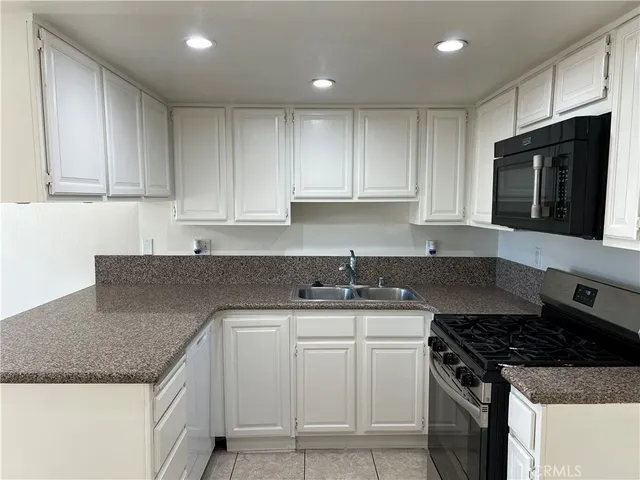 a kitchen with granite countertop a sink stove and cabinets