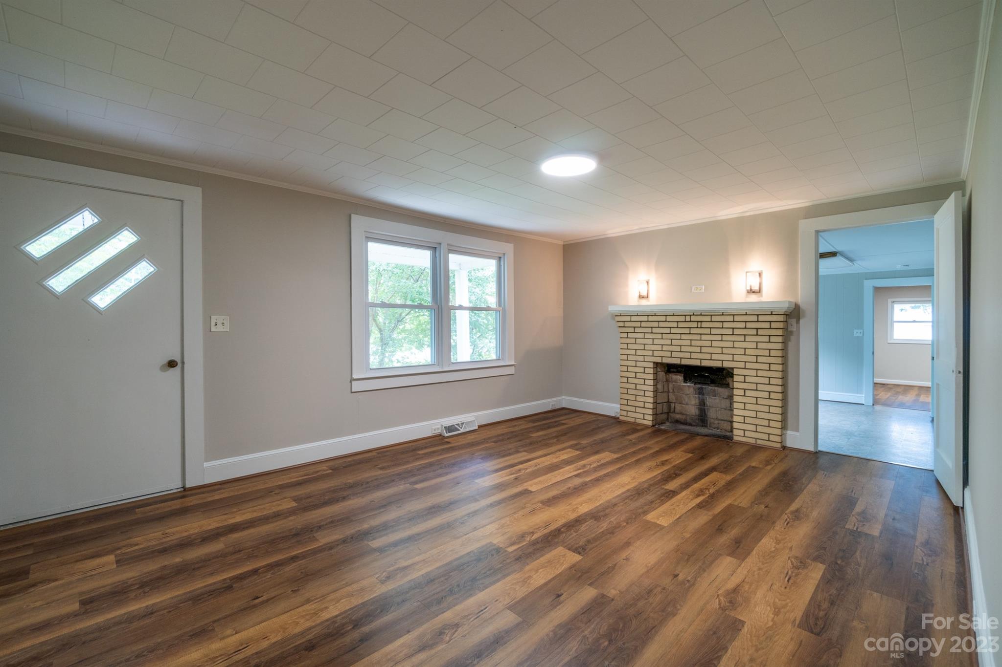 17158 Pond Road Locust, NC 28097 - Photo 5 of 28 an empty room with wooden floor fireplace and windows