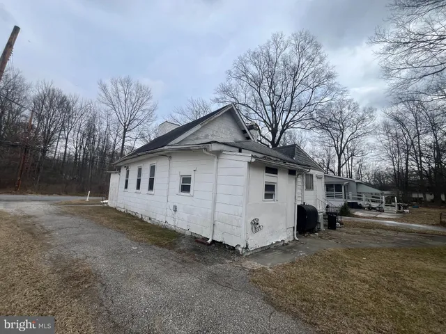 a view of a white house with a large tree in front of it