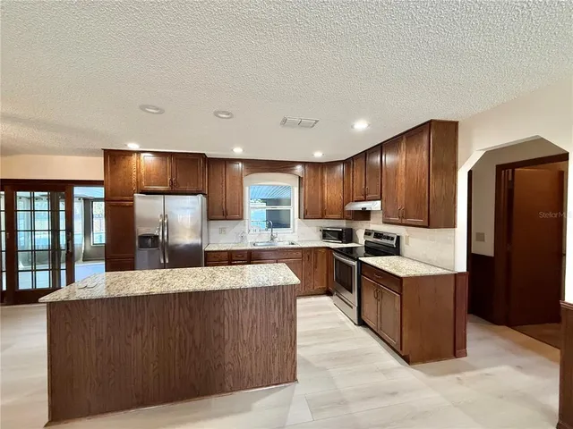 a kitchen with stainless steel appliances granite countertop a refrigerator a sink and a stove