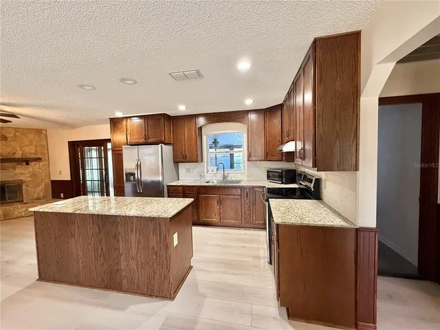 a kitchen with stainless steel appliances granite countertop a refrigerator sink and cabinets