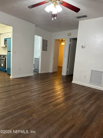 a view of an empty room with wooden floor and a window