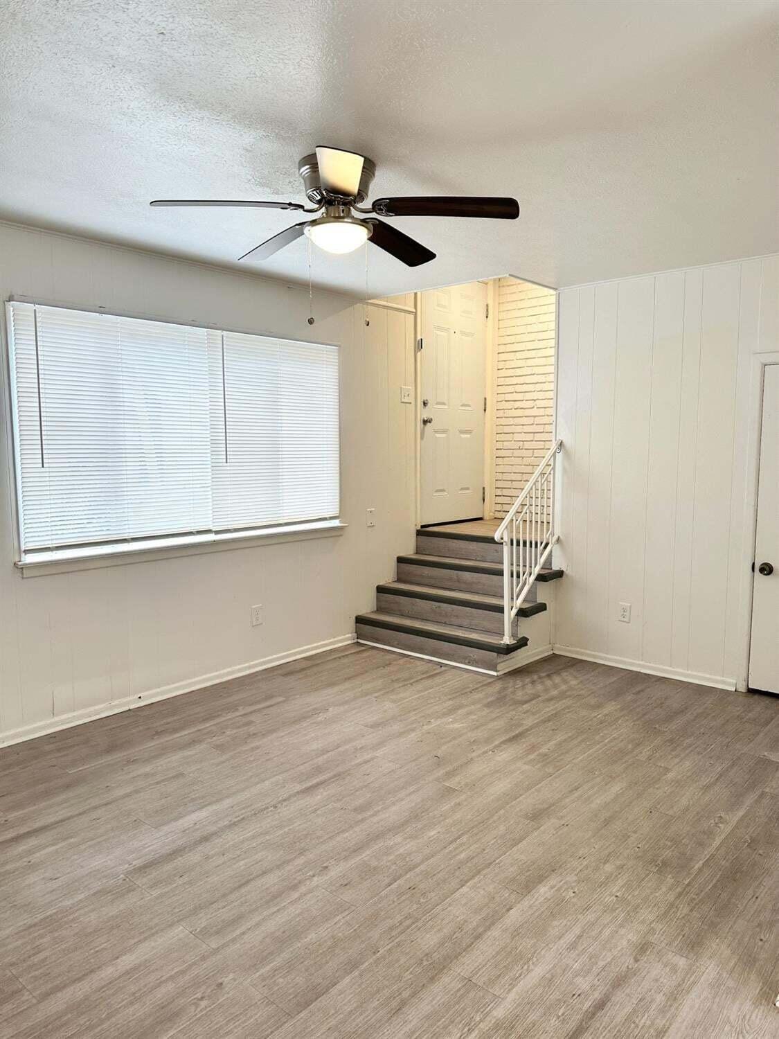 1303 65th Street Lubbock, TX 79412 - Photo 3 of 11 an empty room with wooden floor fan and windows