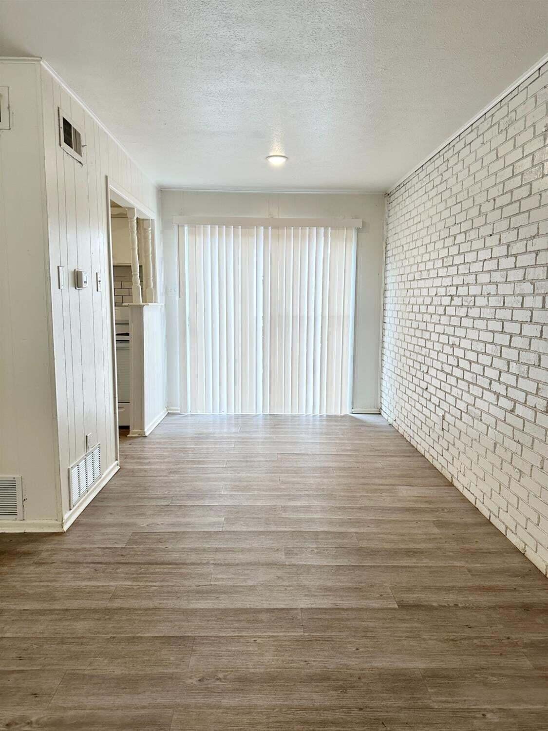1303 65th Street Lubbock, TX 79412 - Photo 4 of 11 a view of an empty room with wooden floor and a window