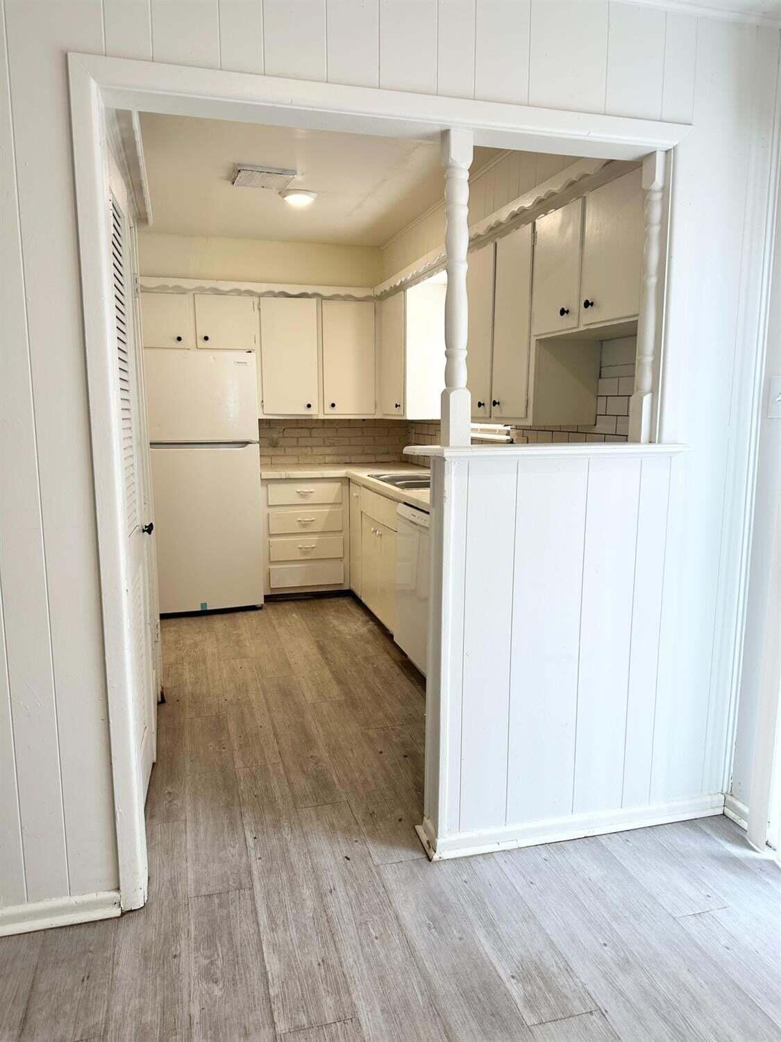 1303 65th Street Lubbock, TX 79412 - Photo 5 of 11 a view of a kitchen with white cabinets and wooden floor