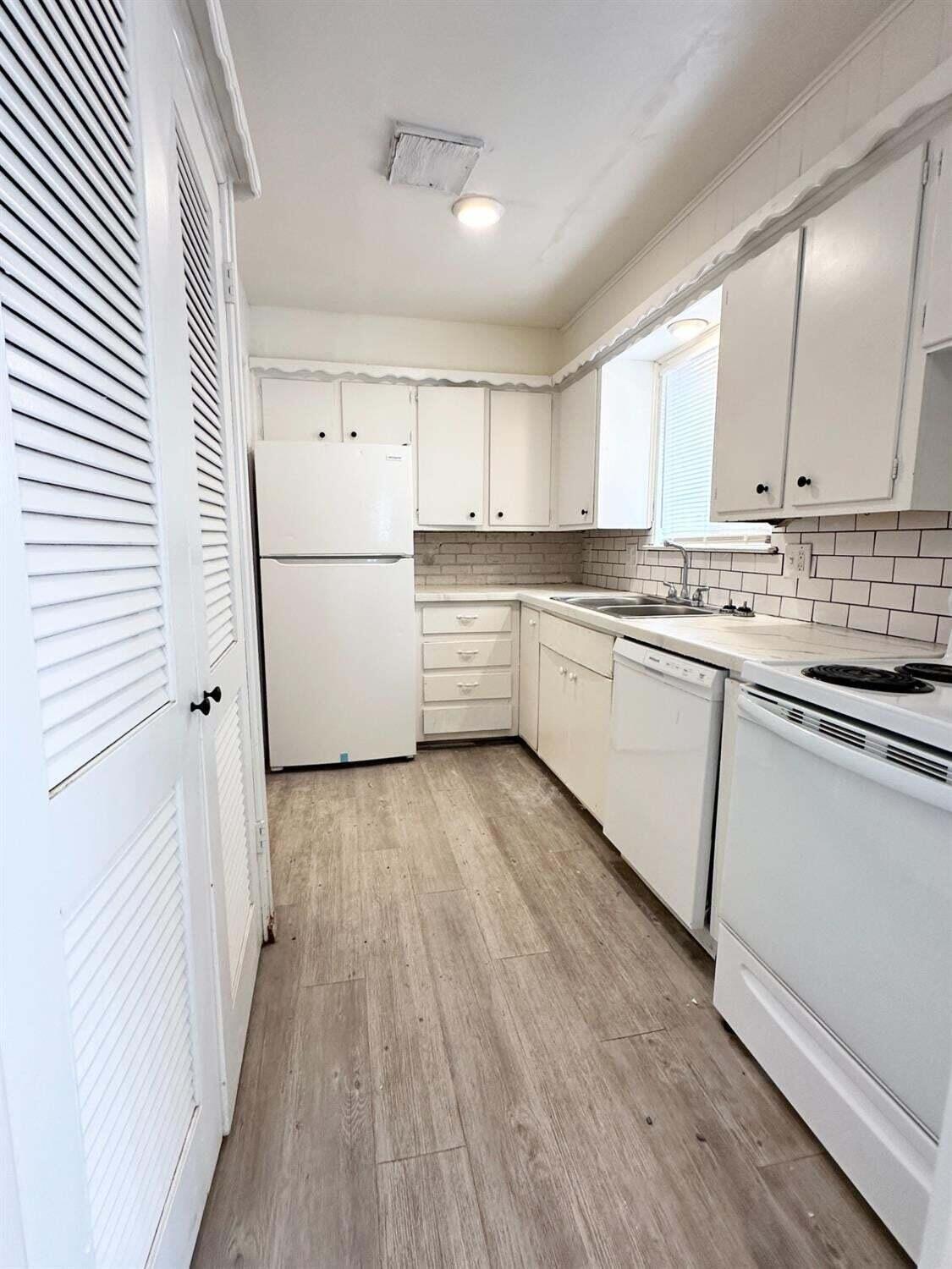 1303 65th Street Lubbock, TX 79412 - Photo 6 of 11 a kitchen with wooden floors and white appliances