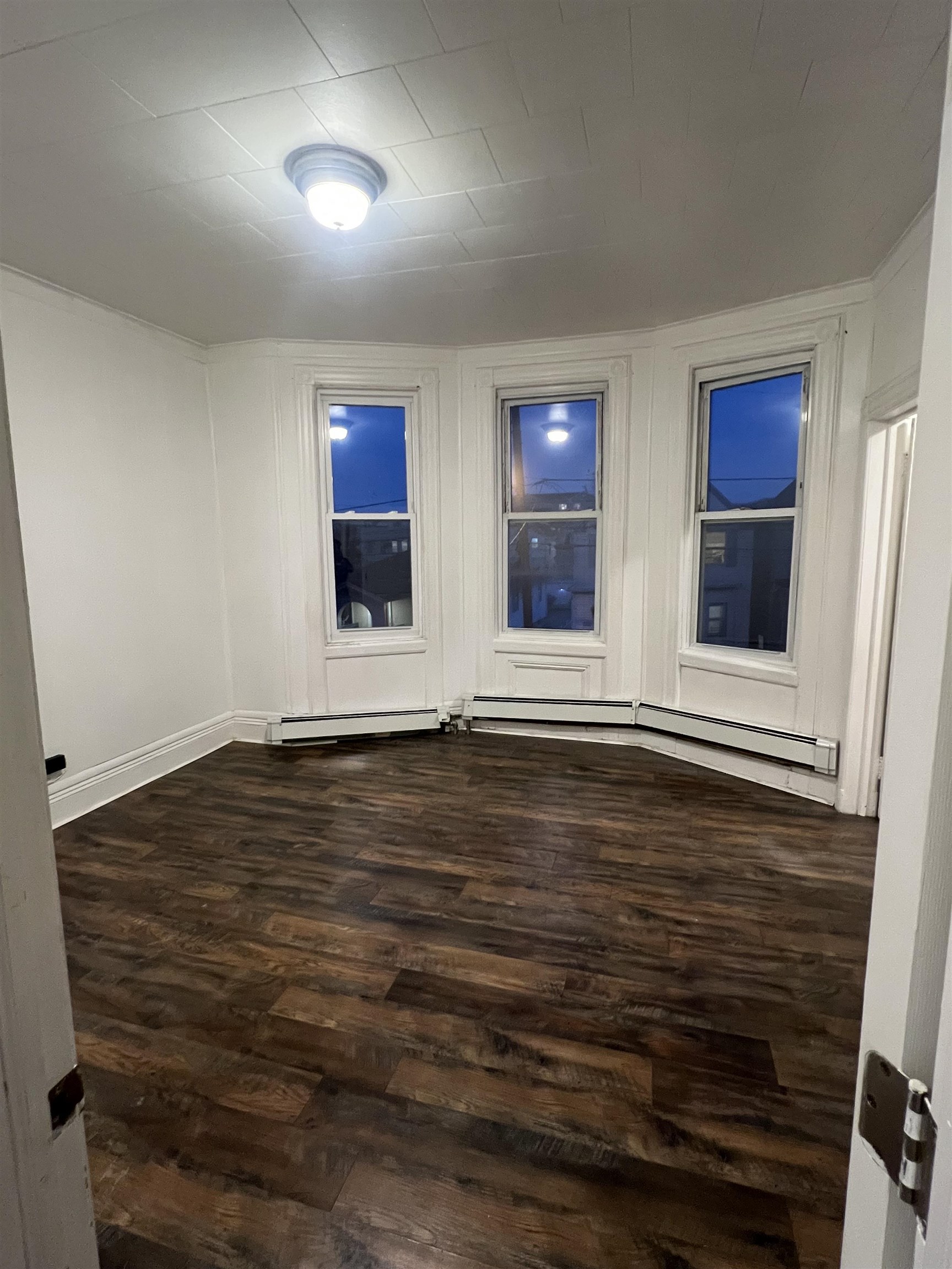 1511 46th Street, Unit 2 North Bergen, NJ 07047 - Photo 2 of 13 a view of an empty room with wooden floor and windows