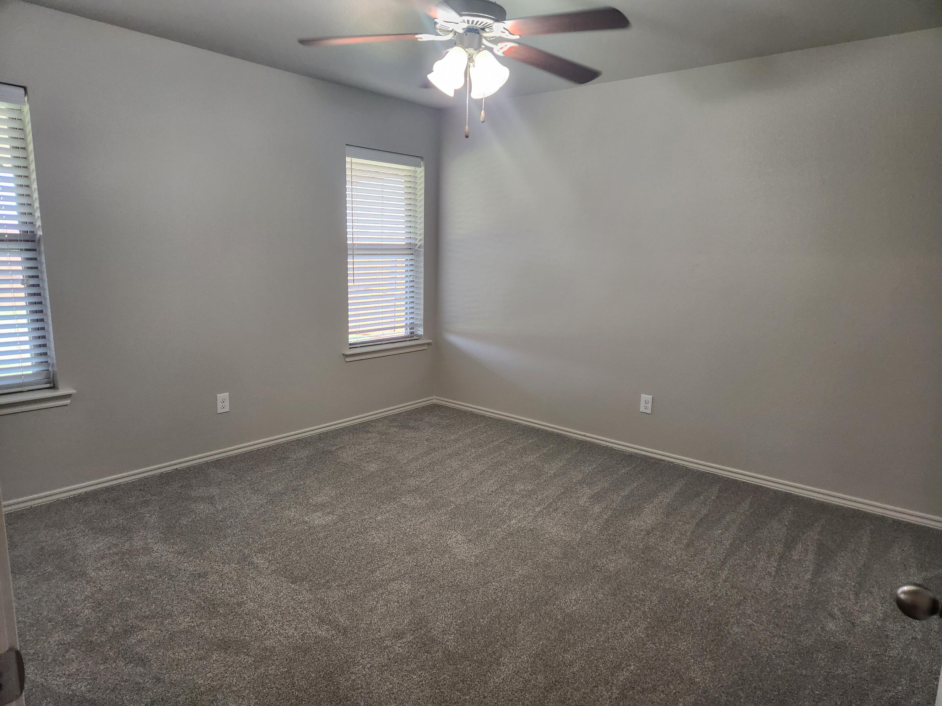 8702 13th Street Lubbock, TX 79416 - Photo 6 of 25 an empty room with a window and a chandelier fan