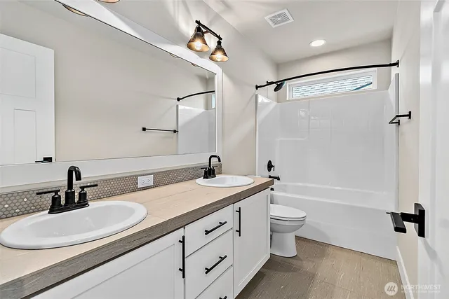a bathroom with a double vanity sink toilet mirror and shower