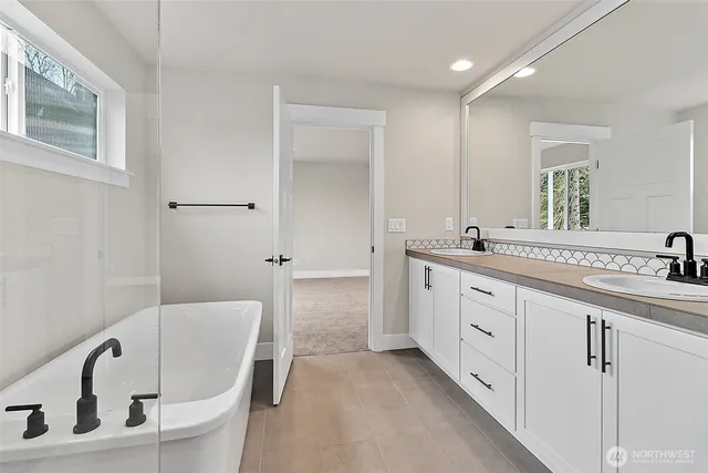 a spacious bathroom with a double vanity sink a mirror and bathtub