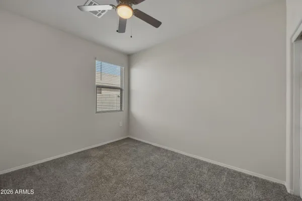 an empty room with a chandelier fan and windows