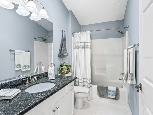 a bathroom with a granite countertop sink mirror vanity and toilet
