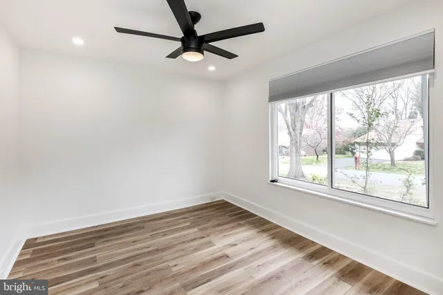 an empty room with wooden floor fan and windows