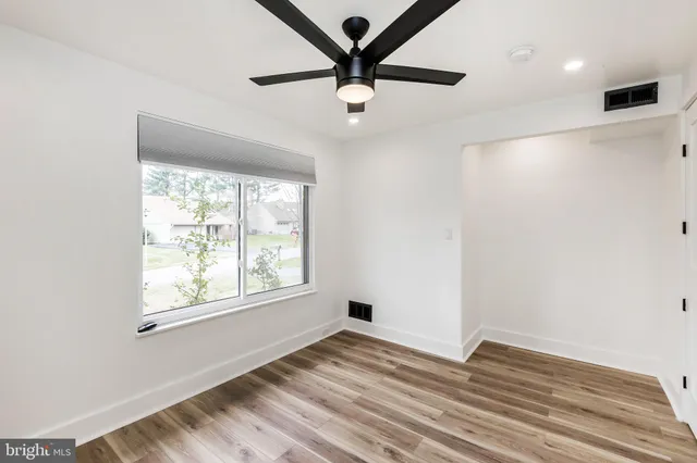 a view of empty room with wooden floor and fan
