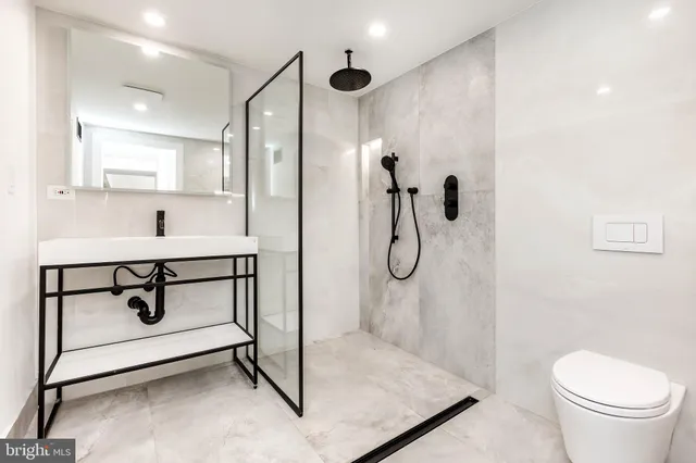 a bathroom with a shower sink mirror and toilet
