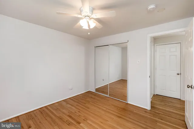 an empty room with wooden floor and fan