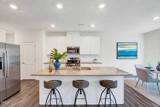 a kitchen with granite countertop a counter space chairs stainless steel appliances and cabinets