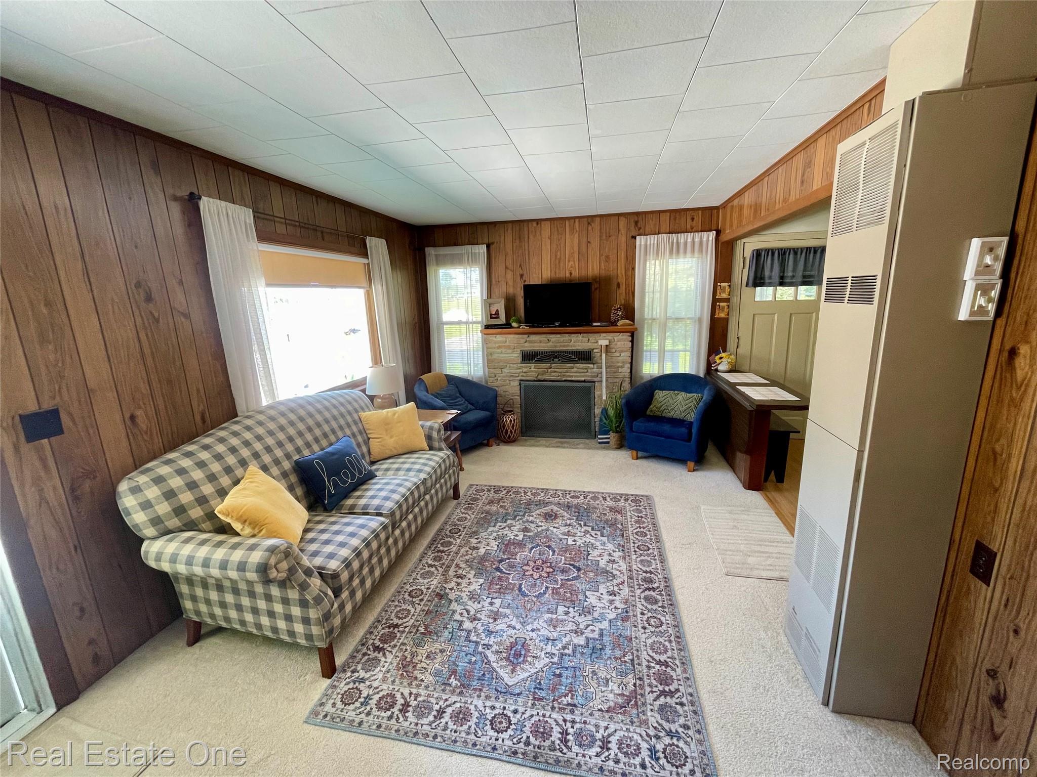 4160 Hawk Road Lincoln, MI 48742 - Photo 19 of 48 Living area featuring wood paneling, light-toned carpet flooring, and a stone-clad fireplace