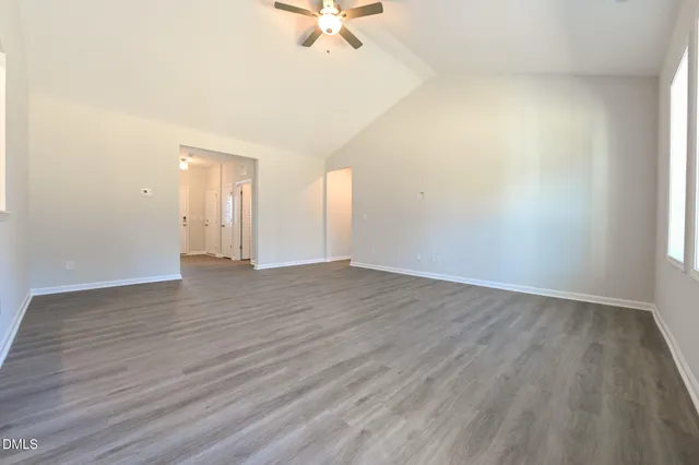 an empty room with wooden floor and a ceiling fan