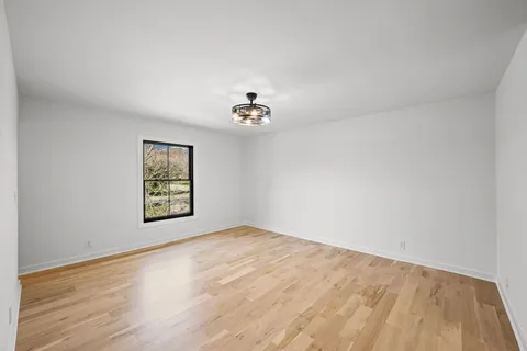 a view of an empty room with wooden floor and window