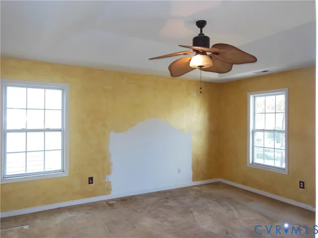 a view of an empty room with window and chandelier fan