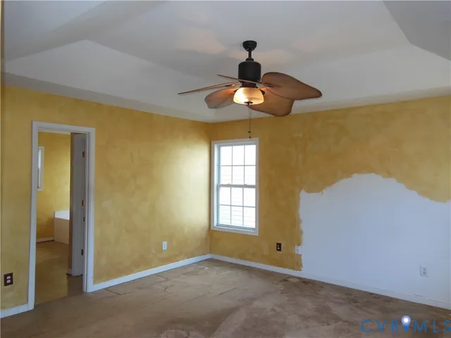 a view of an empty room and chandelier fan