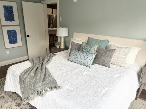 a bed sitting in a bedroom with a white comforter and pillows