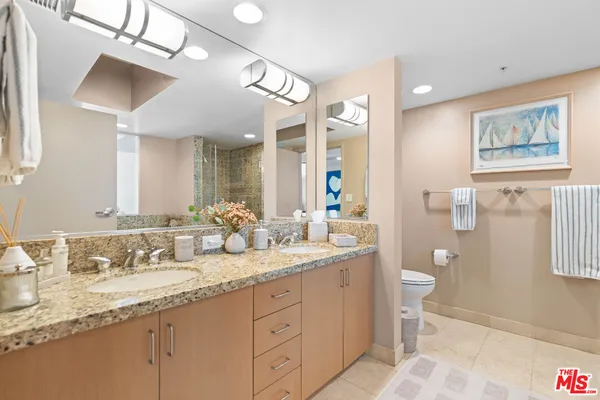 a bathroom with a granite countertop sink mirror vanity and toilet