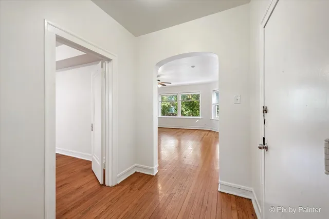 an empty room with wooden floor mirror and windows