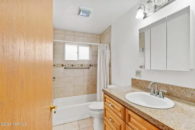 a bathroom with a granite countertop sink toilet mirror vanity and bathtub