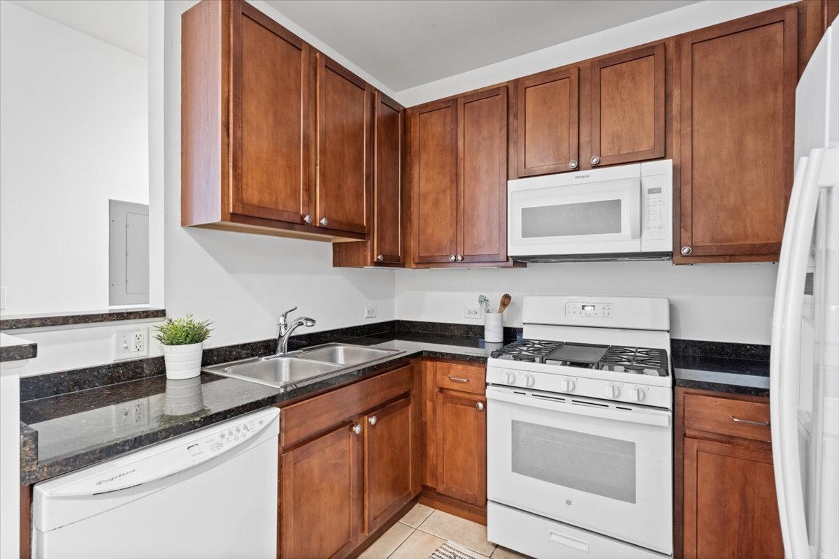 3021 West Armitage Avenue, Unit 208 Chicago, IL 60647 - Photo 7 of 18 a kitchen with stainless steel appliances granite countertop wooden cabinets a stove a sink and dishwasher