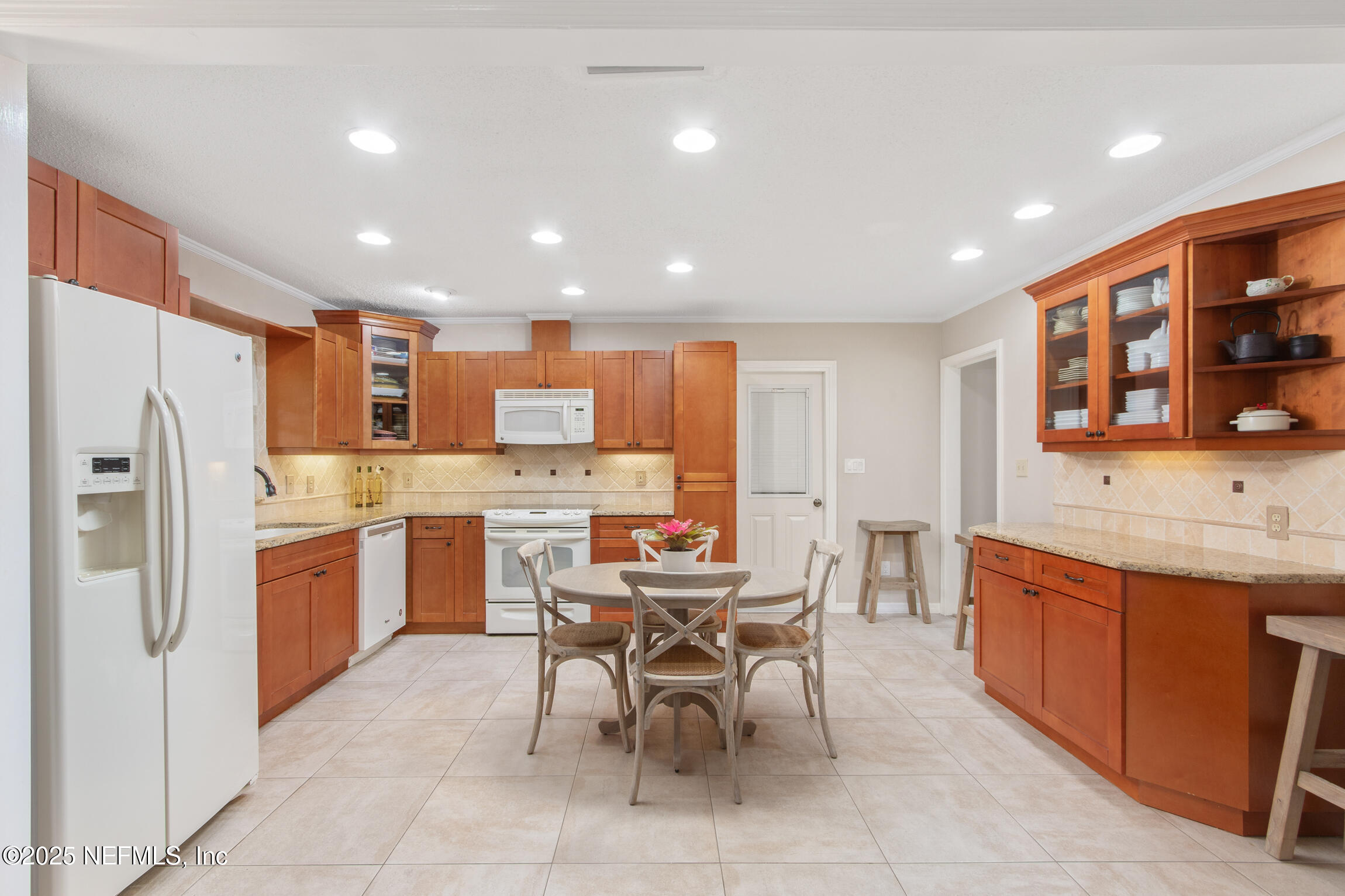 405 Lobelia Road St. Augustine, FL 32086 - Photo 11 of 40 a kitchen with stainless steel appliances kitchen island granite countertop dining table chairs and a refrigerator