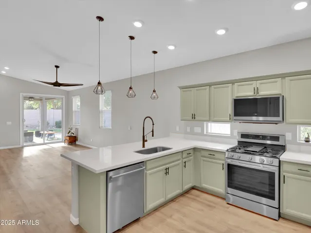 a kitchen with a refrigerator a sink and a stove top oven with wooden floor