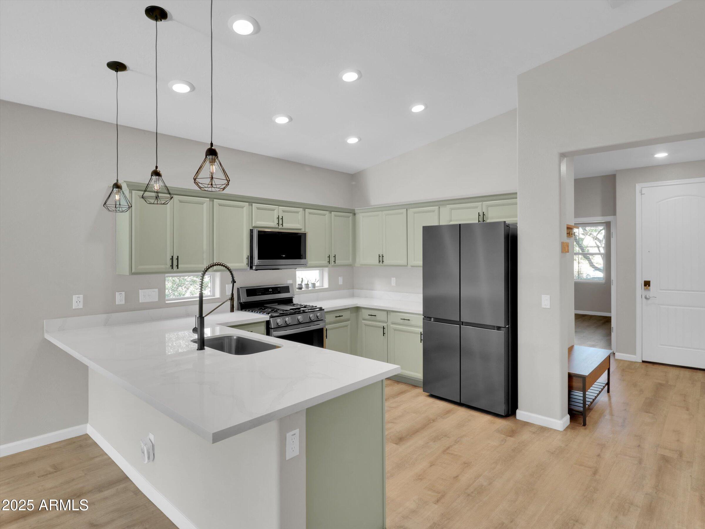 3405 West Alta Vista Road Phoenix, AZ 85041 - Photo 13 of 40 a kitchen with a refrigerator a sink and a stove top oven with wooden floor