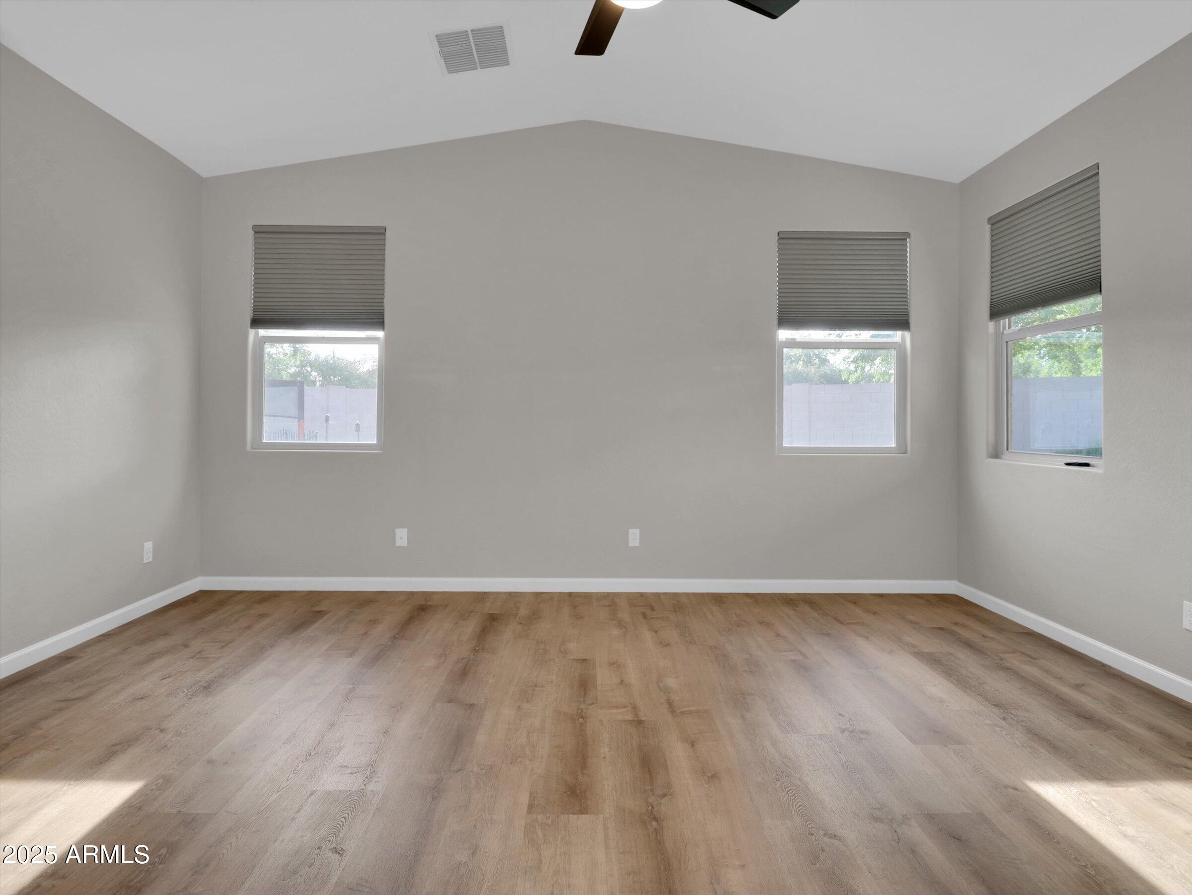3405 West Alta Vista Road Phoenix, AZ 85041 - Photo 19 of 40 a view of an empty room with wooden floor and a window