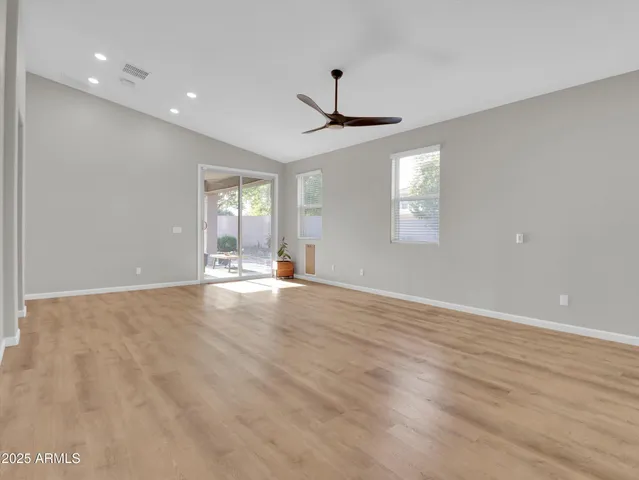 a view of an empty room with wooden floor and a ceiling fan