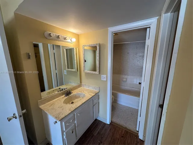 a bathroom with a granite countertop sink a mirror and shower
