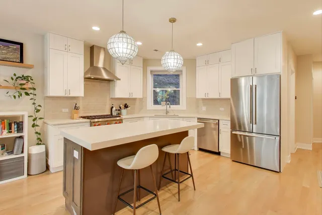 a kitchen with stainless steel appliances granite countertop a sink a stove a refrigerator and island with wooden floor