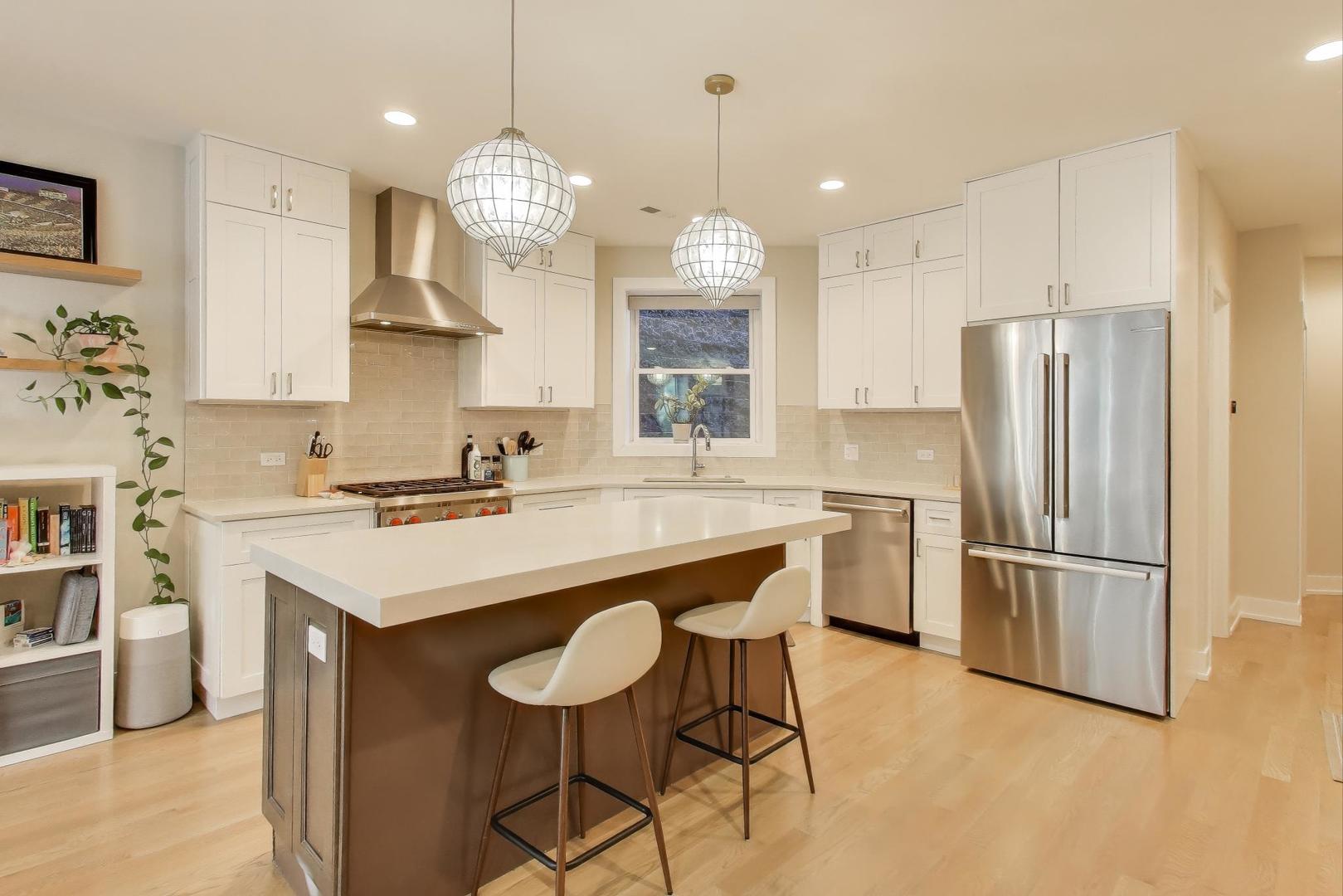 3533 North Fremont Street, Unit 2 Chicago, IL 60657 - Photo 8 of 30 a kitchen with stainless steel appliances granite countertop a sink a stove a refrigerator and island with wooden floor