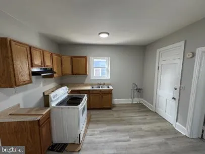 a kitchen with granite countertop a stove a sink a refrigerator and cabinets