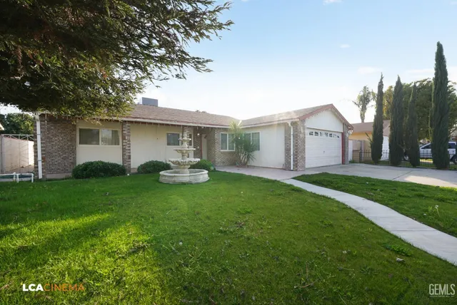 a view of a white house in front of a big yard with large trees