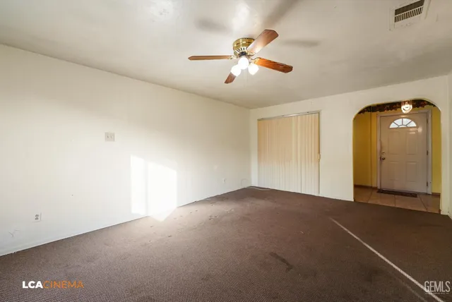 a view of an empty room with a chandelier fan